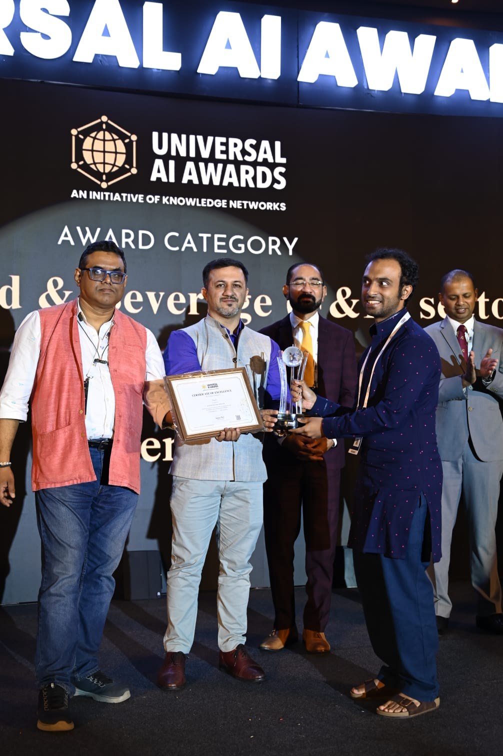 Karthik of Henchu receiving the AI in Food and Beverage sector trophy and certificate on stage at the Universal AI Awards