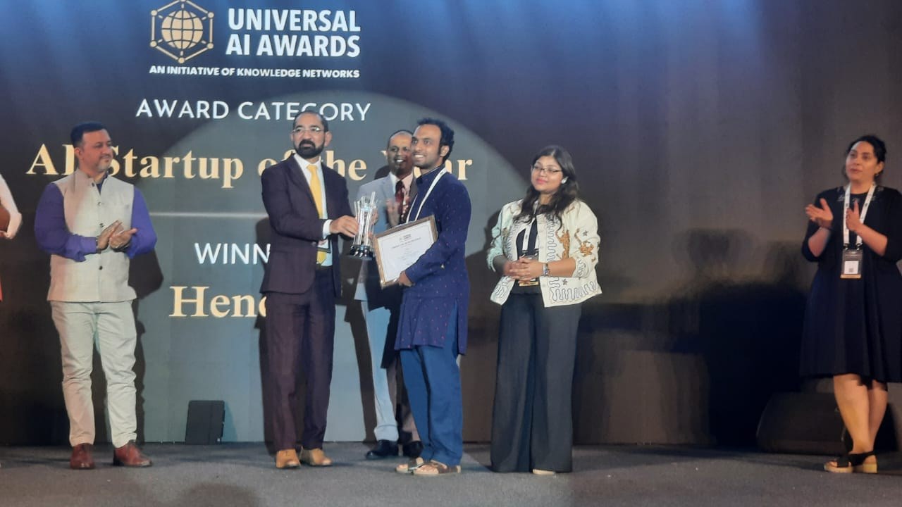 Karthik of Henchu receiving the AI Startup of the Year award on stage, with Henchu named as winner on the screen behind